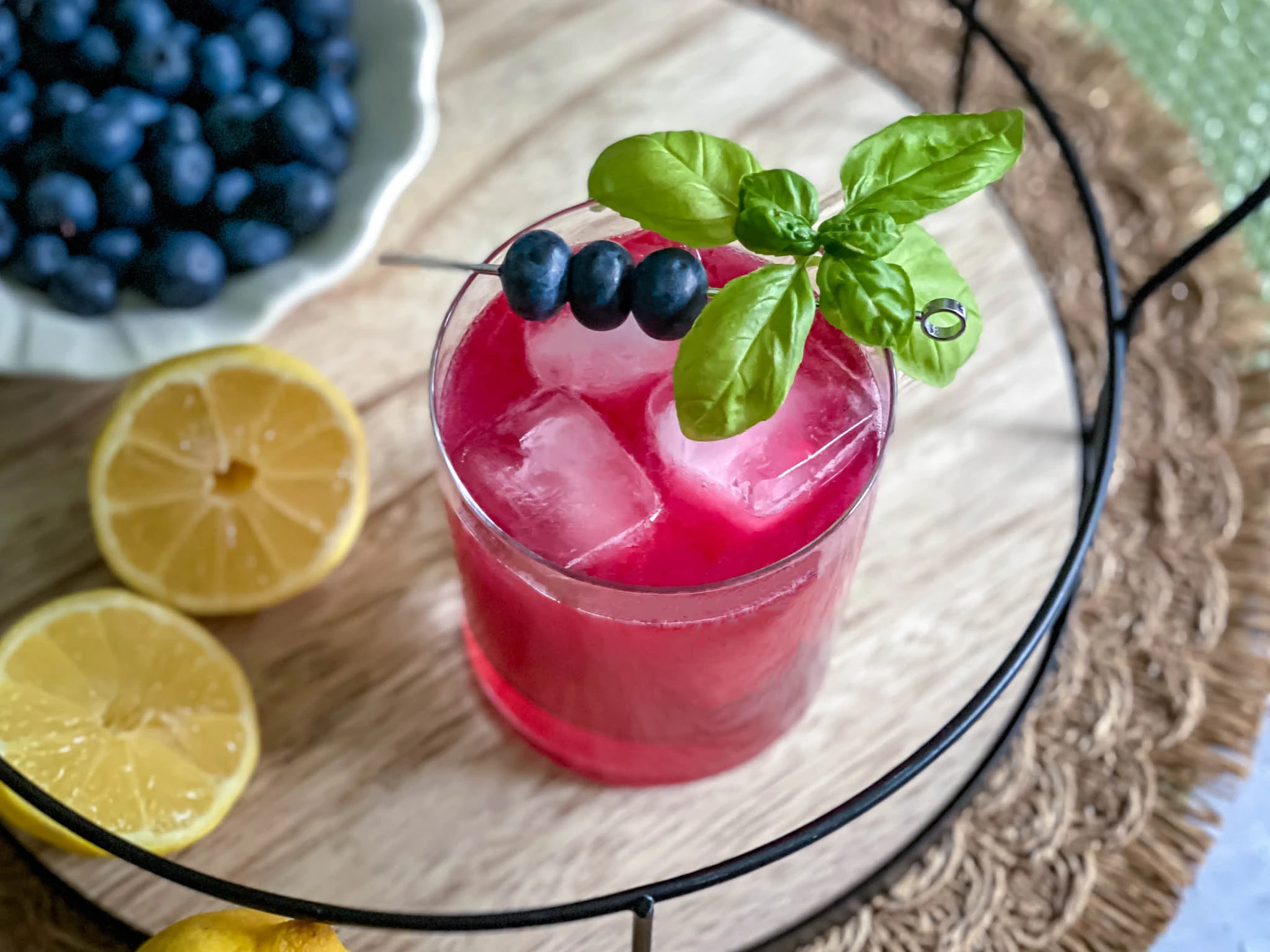 Blueberry basil spritz mocktail with blueberry simple syrup sparkling water fresh basil in a wine glass for 4th of July