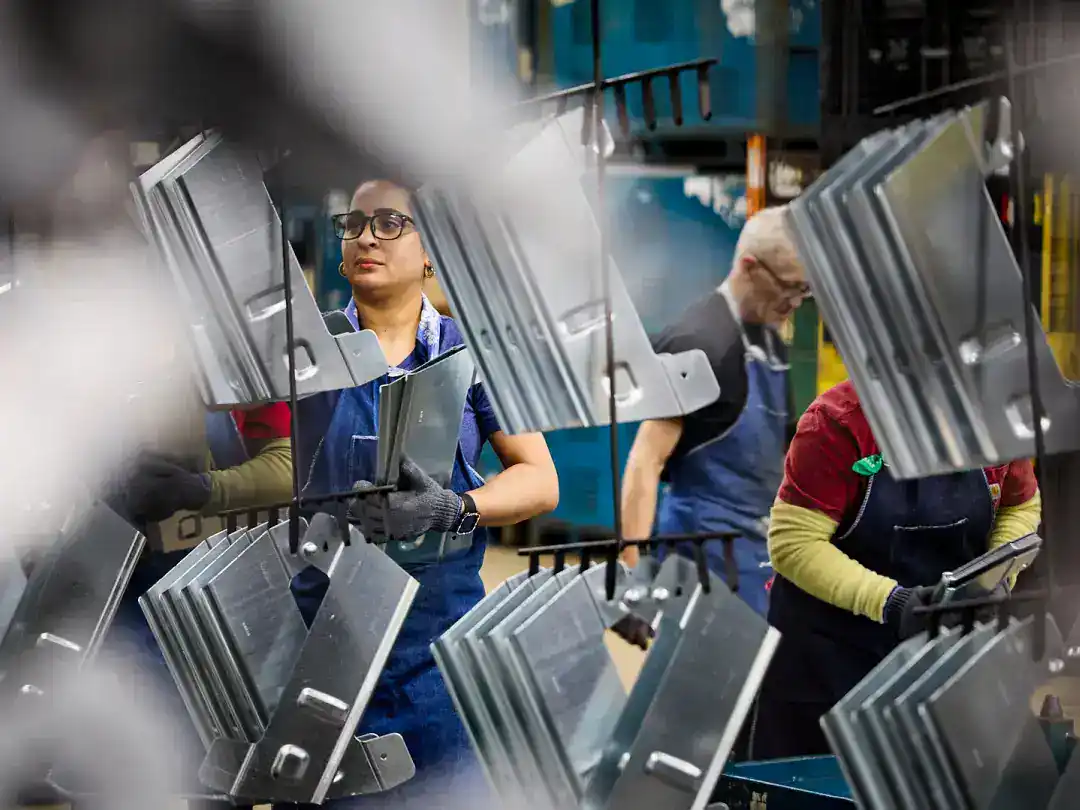 Workers assembling metal components in a factory setting.