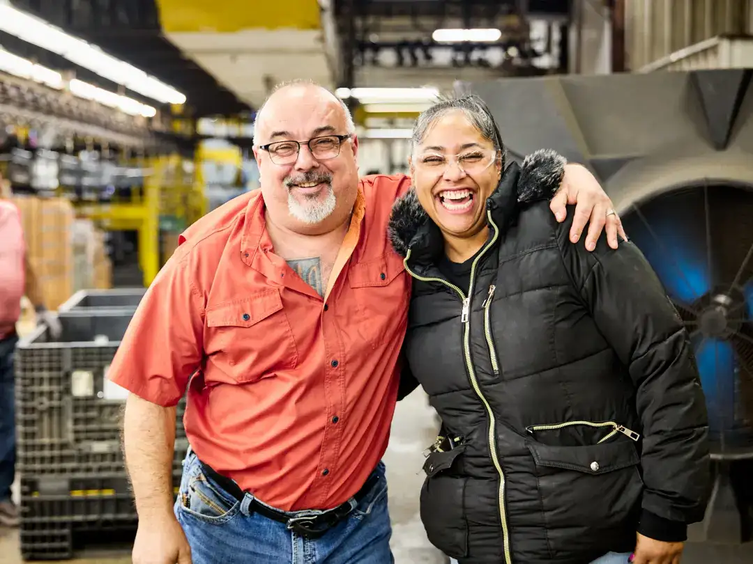 Smiling man and woman in factory, industrial environment, teamwork, happiness.
