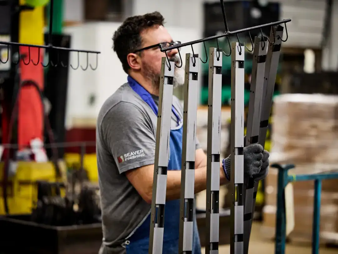 Worker assembling metal storage racks in industrial warehouse setting.