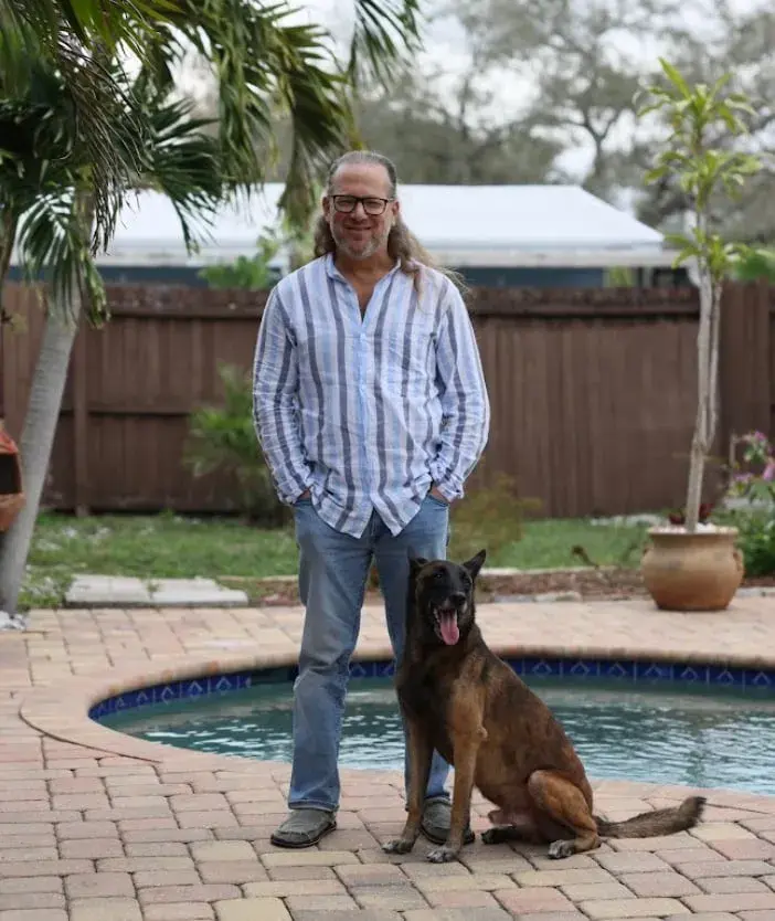 Man standing by a pool with a german shepherd dog during a dog training session.