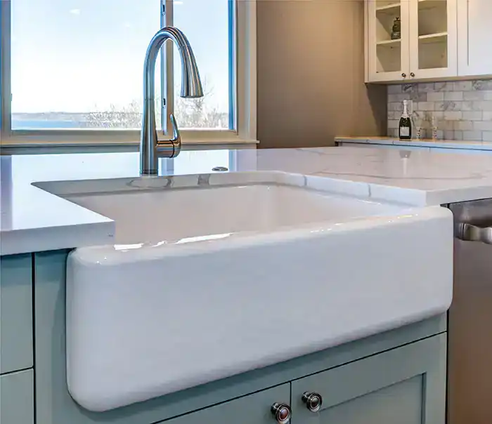 Farmhouse apron sink with modern kitchen faucet and window view.