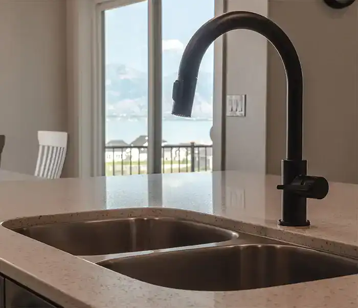 Modern undermount stainless steel sink with black faucet in kitchen.