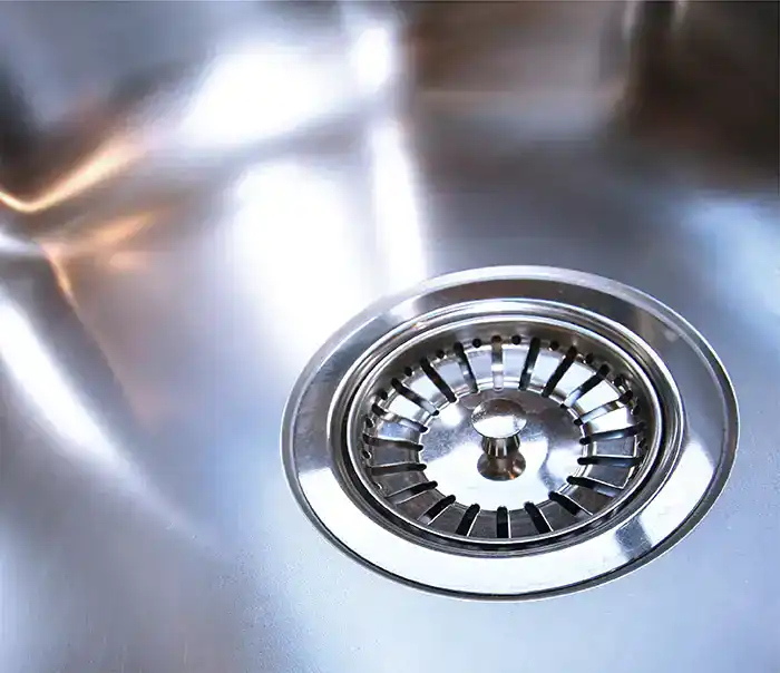 Close-up of a stainless steel sink drain with a strainer.