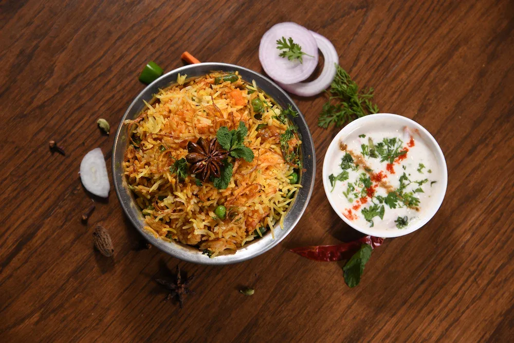 Veg,Biryani,In,Handi,With,Raita,On,Wooden,Background