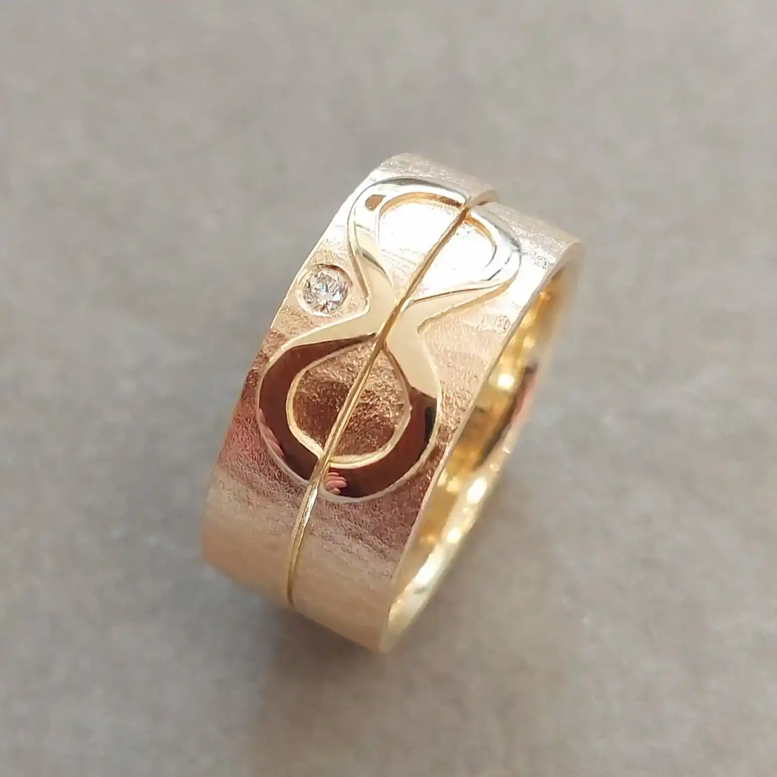 ein paaar Goldringe mit unendlichem Symbol und einem kleinen Diamanten, in einem schlichten Design mit einer matten Oberfläche.