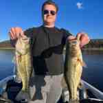 A man holds up two largemouth bass caught with Badock Fishing Guide Service while at Table Rock Lake in southwest Missouri near Branson.