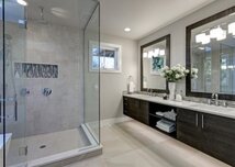 Double sink with custom vanity mirror and frameless glass shower doors in luxury bathroom
