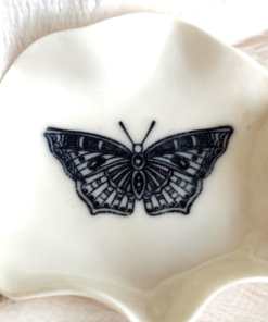 A small, white scalloped "Butterfly Ring Holder" featuring a black butterfly design (6.5 cm x 6.5 cm).