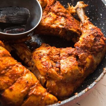 A close up chicken leg in a pan, ready to smoke.