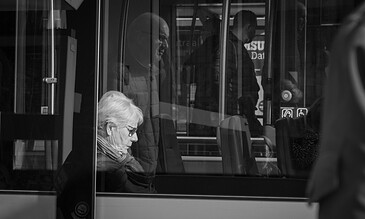 Older woman sleeping on public bus, black and white urban photography, capturing everyday moments of serenity and transit.