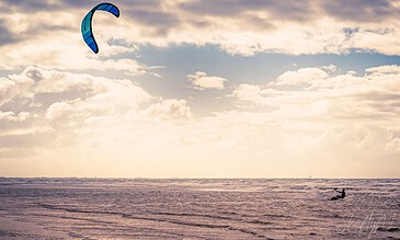 1. Colorful kite surfer gliding over the ocean waves during sunset, capturing a dynamic and vibrant seaside scene.
