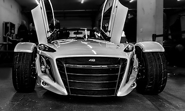 A sleek, modern sports car with distinctive Lamborghini-style scissor doors open in an indoor garage, capturing a moment of automotive elegance and innovation.