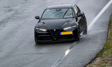 Alfa Romeo car drifting on wet road during rain, showcasing dynamicmotion and style in automotive photography.