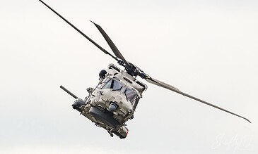 Close-up of a military helicopter flying through the sky, highlighting its rotor blades and sleek design in a high-altitude environment. Aerial view of a military helicopter in flight against a cloudy sky, showcasing advanced aviation technology and dynamic movement.