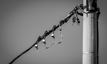 A power line on a utility pole in black and white, close-up shot.