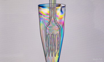 Holographic glass featuring a fork and straw, showcasing stunning rainbow effects and light reflections, ideal for special event photography. Colorful iridescent glass with fork and straw, vibrant and artistic beverage presentation, perfect for capturing special moments in photography.