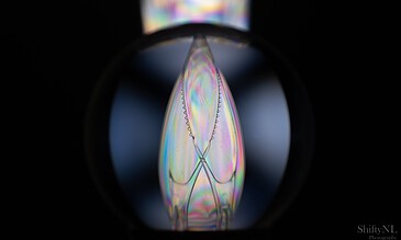Close-up of a plastic glass surface with rainbow iridescence and intricate patterns, highlighting the delicate beauty and vibrant colors in a dark setting. Colorful macro shot of a plastic glass showing iridescent patterns and delicate surface textures, captured through a macro lens with a black background for high contrast.