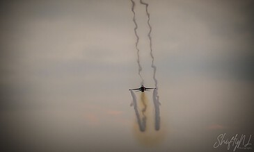 A sleek aircraft soaring through the sky, leaving vapor trails behind against a muted, cloudy background. Aero plane flying through the sky with vapor trails behind, captured during flight.