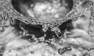 Shifting water droplets captured in black and white, showcasing detailed ice formations and light reflections for stunning nature photography.
