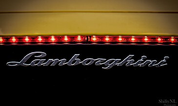 Lamborghini logo illuminated at night, showcasing luxury car branding with vibrant lighting and sleek design.