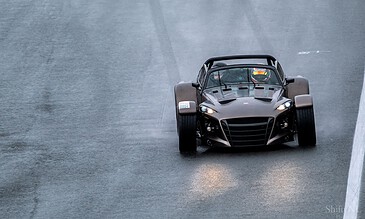 1. Sleek black race car on wet race track during a high-speed racing event, showcasing professional motorsport action and dynamic driving.