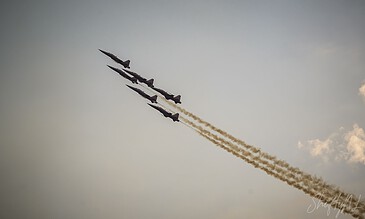 Spectacular aerial display captured by ShiftyNL Photography showcasing precision flying and dynamic motion. Aviation jets flying in formation with smoke trails against a cloudy sky.