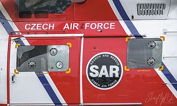 Close-up of a Czech Air Force Search and Rescue (SAR) helicopter with red, white, and blue markings and SAR emblem, showcasing detailed exterior features and emergency equipment.