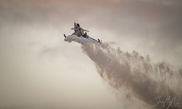 A sleek military jet performing an aerial maneuver, leaving a trail of vapor against a cloudy sky, showcasing aviation photography. Aero L-39 Albatros jet aircraft soaring through the sky with a dramatic vapor trail during a flight display.