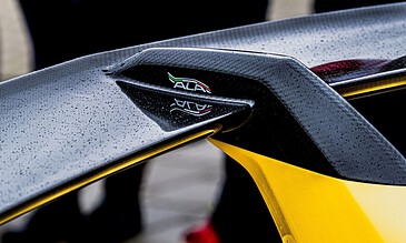 1. Close-up of a sleek racing car winglet showcasing carbon fiber material and vibrant yellow accents for high-performance motorsport design.