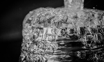 1. Close-up of water bubbles forming in a glass with liquid pouring, black-and-white photography emphasizing texture and movement.
