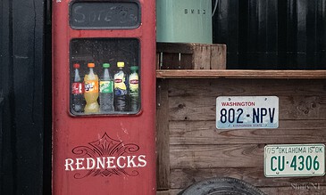 1. Vintage red soda vending machine with assorted bottled drinks, rustic wooden background with license plates, showcasing nostalgic and authentic outdoor photography.