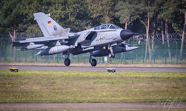 A sleek military aircraft in flight, captured during takeoff on a clear day, showcasing its aerodynamic design and power. Aero L-159 Alca fighter jet taking off from runway with trees in background.