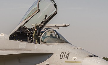 Close-up of a fighter jet cockpit with a pilot inside, ready for flight, showcasing detailed aircraft features and a clear sky background. Aero fighter jet cockpit with pilot preparing for takeoff, close-up view.