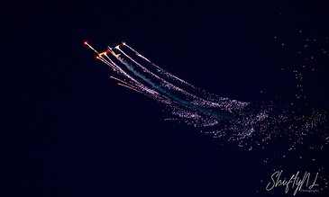 A colorful fireworks display streaking across a dark night sky, leaving sparkling trails and bright bursts.