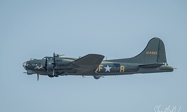 Aviation photography of a vintage military aircraft flying in a clear blue sky.