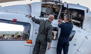 Aeroengine maintenance technicians inspecting a helicopter engine during a technical demonstration.