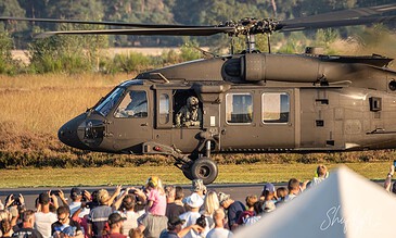 AeroMed helicopter landing during an outdoor event with a crowd of spectators watching attentively.