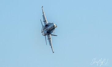 F-16 fighter jet soaring through a clear blue sky during an airshow.