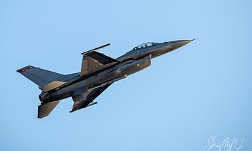 A flying fighter jet soaring through a clear blue sky, showcasing sleek design and aerodynamic features.