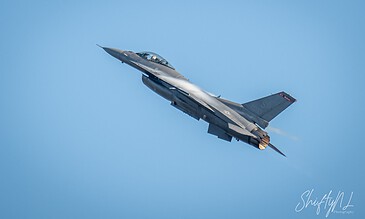 F-16 fighter jet soaring through a clear blue sky during flight.