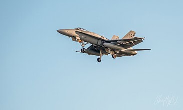 Dynamic capture of an F-18 fighter jet soaring through the sky during flight. F-18 fighter jet in mid-flight against clear blue sky, showcasing agility and power.