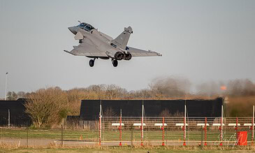Dassault Rafale fighter jet coming in for landing at a military airfield during daylight. Dassault Rafale fighter coming in for landing with a clear sky background.