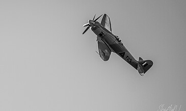 A vintage propeller aircraft flying through the sky, captured in black and white for a timeless and dramatic effect.