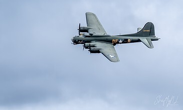 A vintage World War II military aircraft flying against a cloudy sky, showcasing detailed design and historic significance.