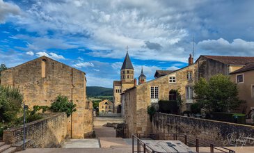 Picturesque medieval architecture with stone facades and tall church spires in a charming old town. Stone historic buildings and church towers in a scenic European village under a blue sky with clouds.