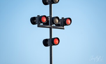 Up of a traffic light signal with red lights illuminated, set against a bright blue sky, highlighting traffic control at busy intersections. A detailed traffic light signal with multiple lights against a clear blue sky, used to control vehicle and pedestrian movement at intersections.