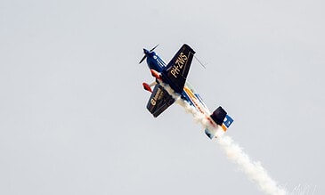 The Leaseweb Extra pulling up. Extra aerobatic aircraft PH-ZWS in Leaseweb livery climbing with smoke on at the Leaseweb Texel Airshow, Texel International Airport, the Netherlands, August 2018.