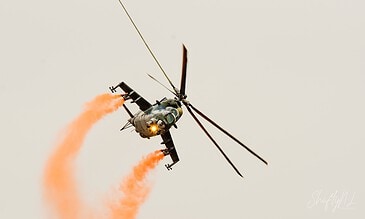Hind turning hard with orange smoke. Czech Air Force Mi-24 Hind in a steep turn trailing orange smoke from its wing pylons at the Leaseweb Texel Airshow, Texel International Airport, the Netherlands, August 2018.