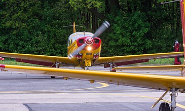 Through the wing. Yellow SF.260 trainer taxiing head-on, framed by the wing of another SF.260 at Beauvechain Air Base, Belgium, April 2018.